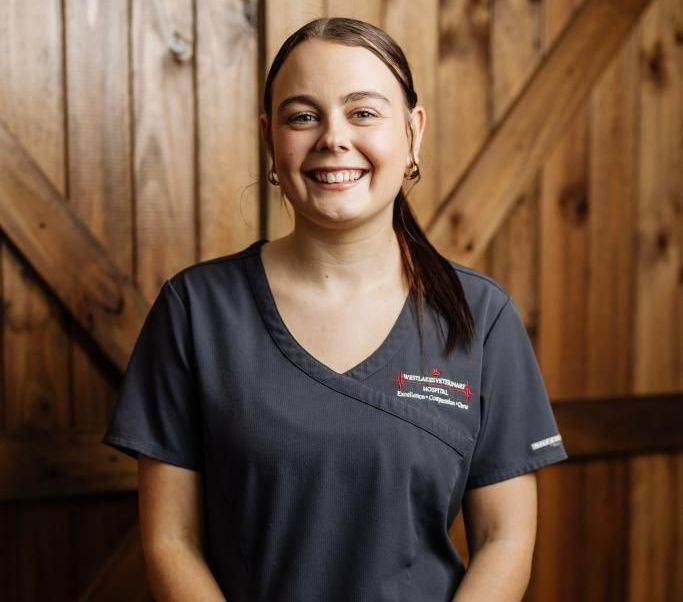 Woman smiling in front of a wooden backdrop — Westlakes Veterinary Hospital in Fennell Bay, NSW