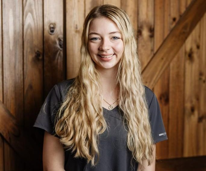 Woman with long blonde hair in front of a wooden wall — Westlakes Veterinary Hospital in Fennell Bay, NSW