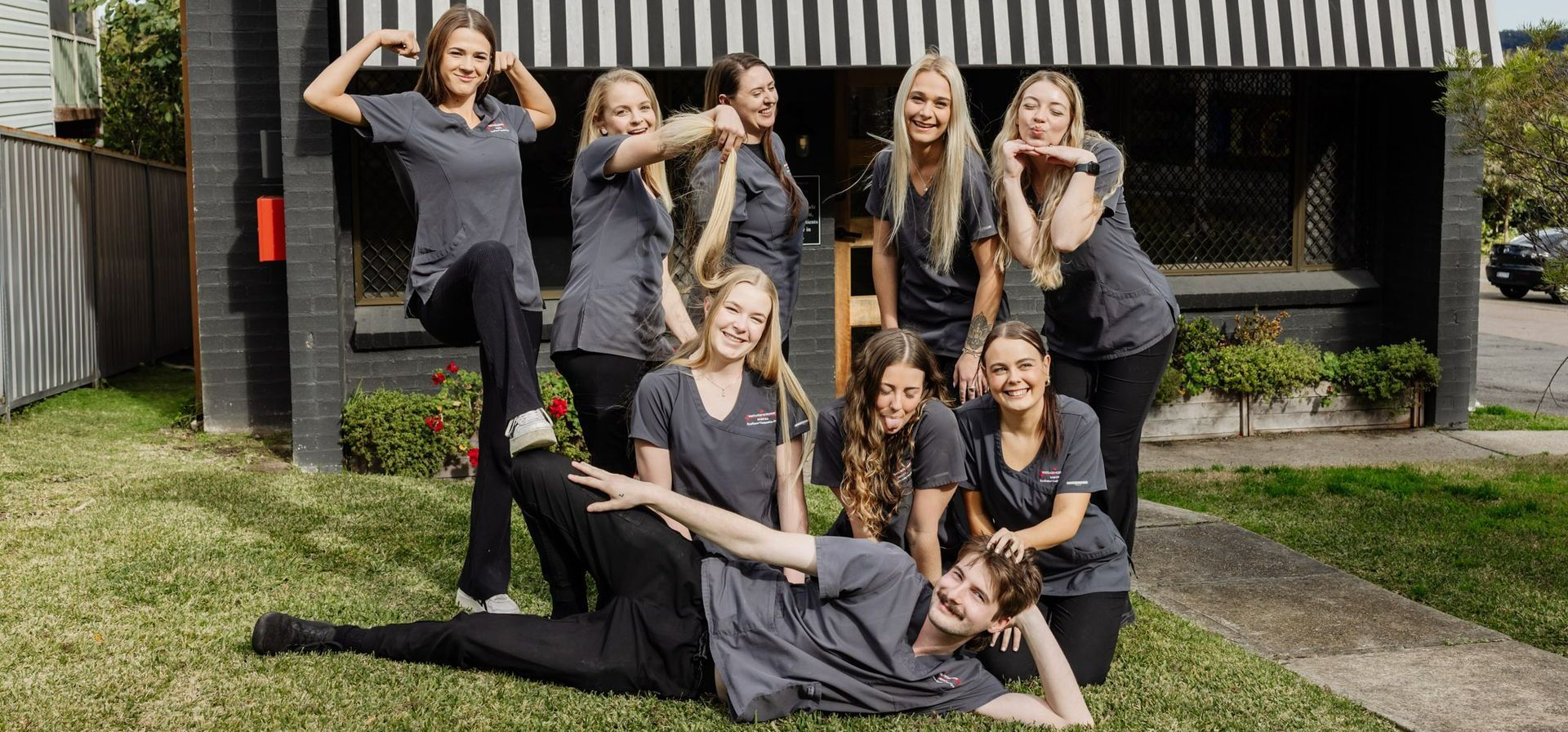 Group of people in matching shirts posing on grass — Westlakes Veterinary Hospital in Fennell Bay, NSW
