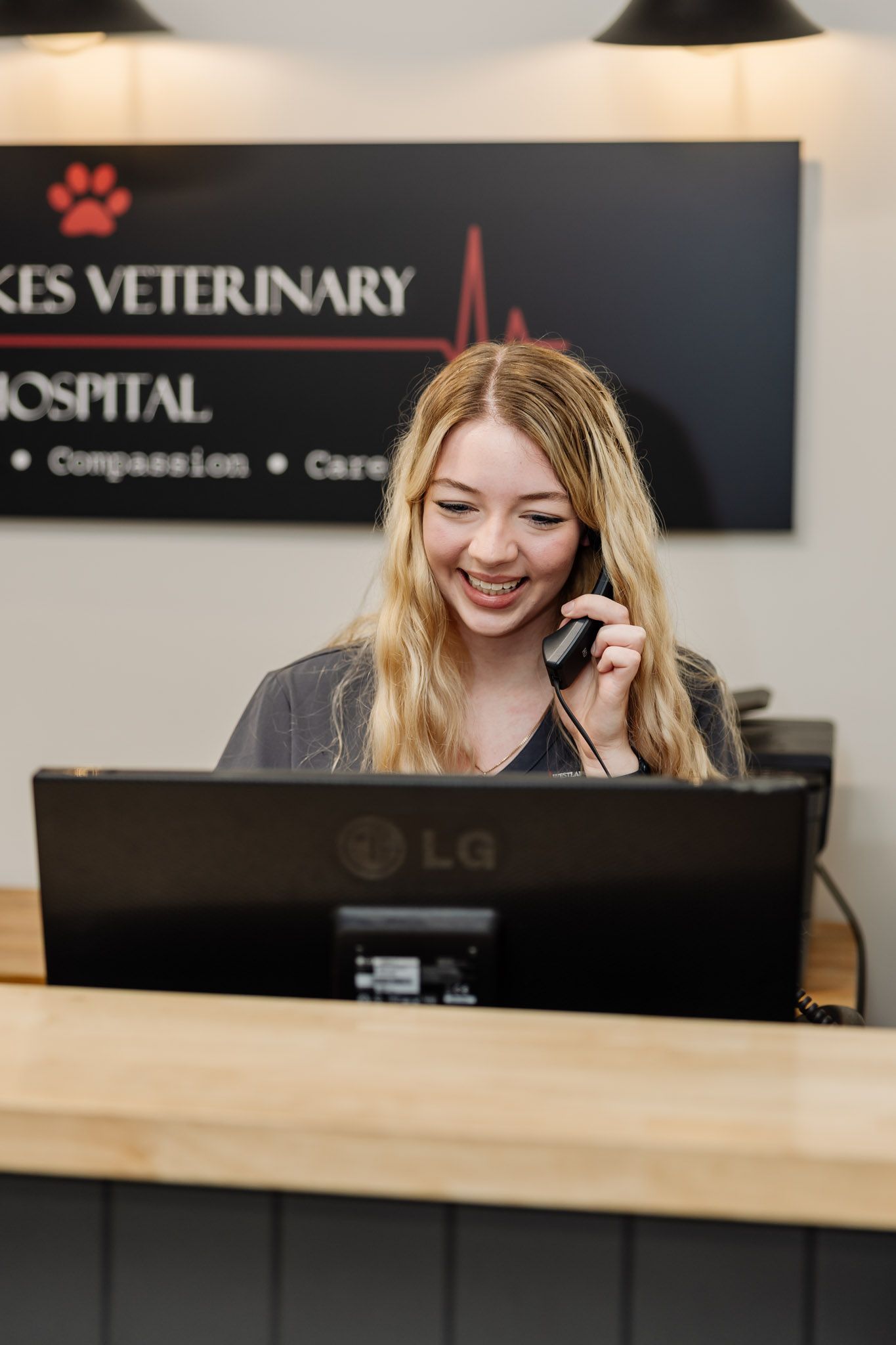 A lady sitting at reception smiling in front of a computer — Westlakes Veterinary Hospital in Fennell Bay, NSW