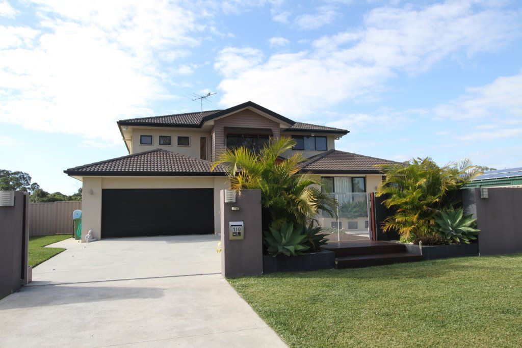 A Large House With a Black Garage Door and a Mailbox — Peterson Property Valuations In Caloundra West, QLD