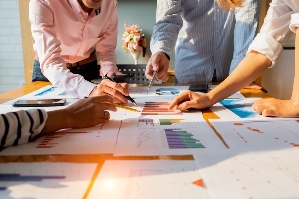 People Collaborating Over Charts and Graphs on a Table — Peterson Property Valuations In Caloundra West, QLD