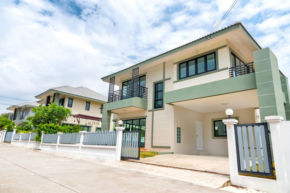 A Large White and Green House With a Fence in Front of It — Peterson Property Valuations In Caloundra West, QLD