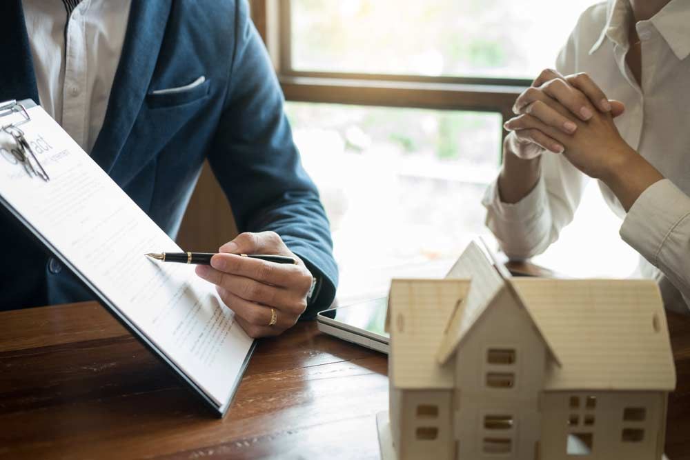 A man and a woman are sitting at a table — Peterson Property Valuations In Caloundra West, QLD