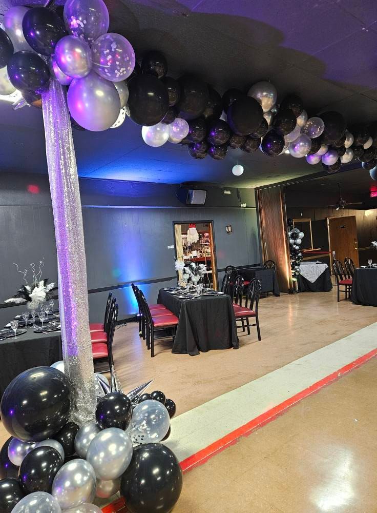 A room with tables and chairs and balloons hanging from the ceiling.