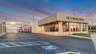 Storage facility with a beige office building, a grey stone wall, and a blue handicap parking space.