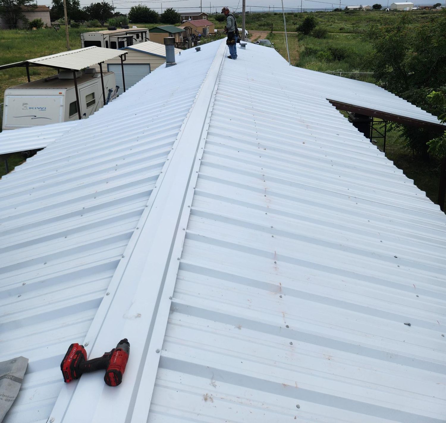 A man standing on top of a white metal roof