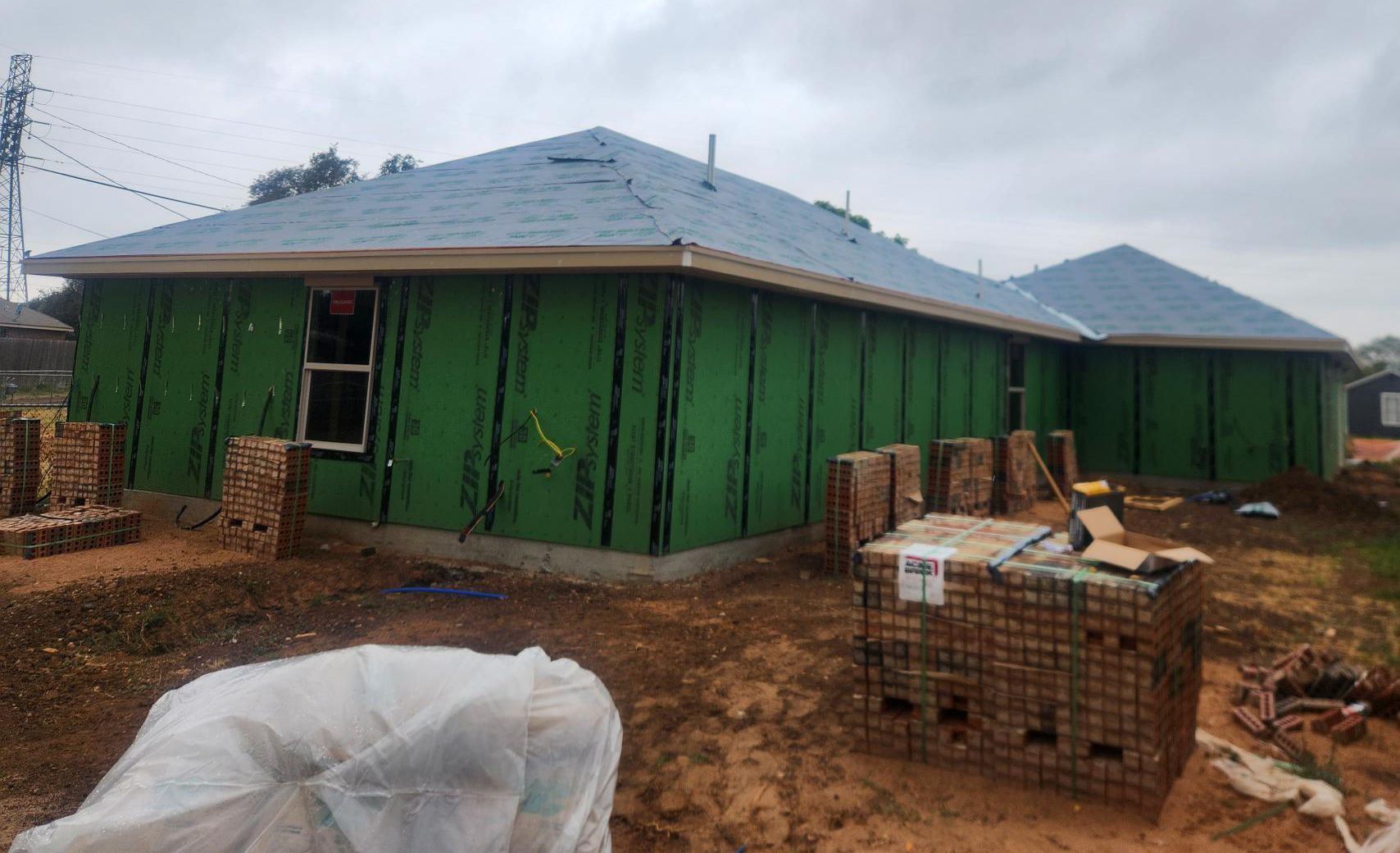 A house is being built with green siding and a blue roof.