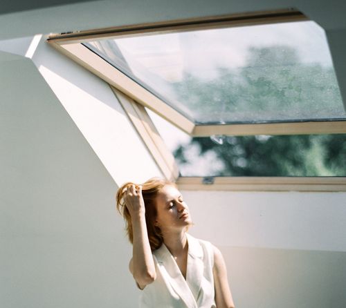 A woman in a white shirt is standing in front of a skylight