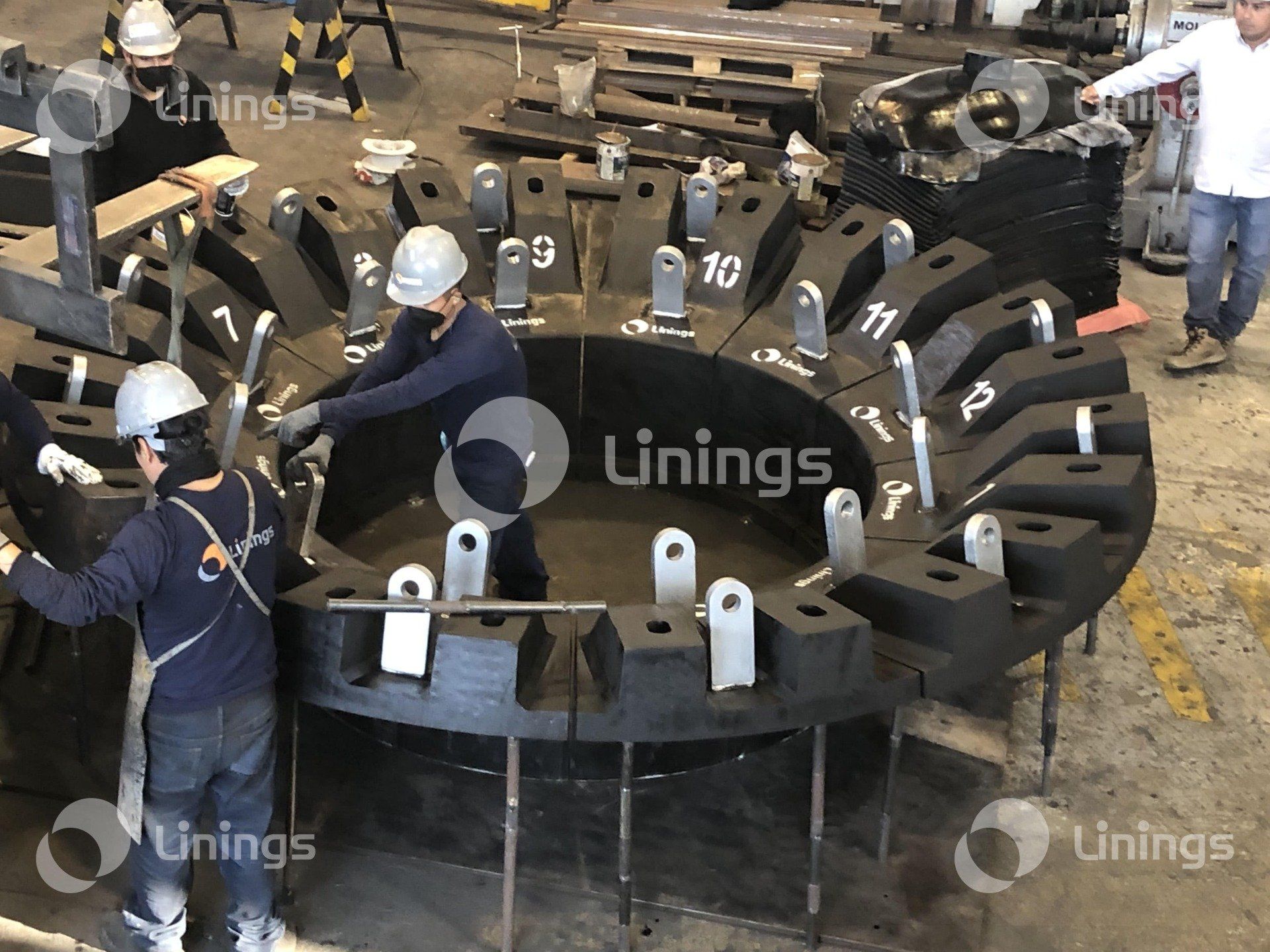 Dois homens estão trabalhando em uma grande peça de metal em uma fábrica.