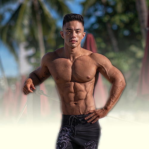 Andee Teo is standing on a beach with his hands on his hips.