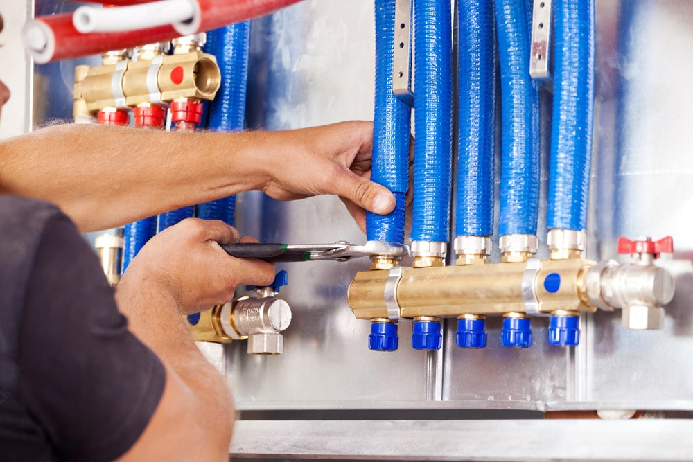 A man is working on a heating system with a pair of pliers.