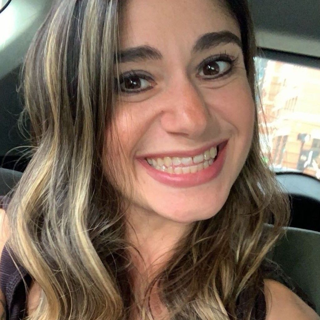 A woman is smiling while sitting in a car.