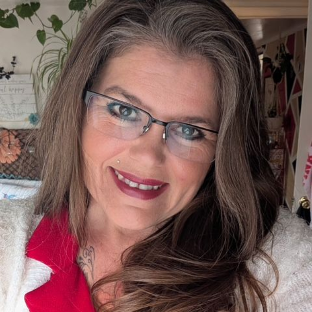 A woman with long brown hair is smiling for the camera.