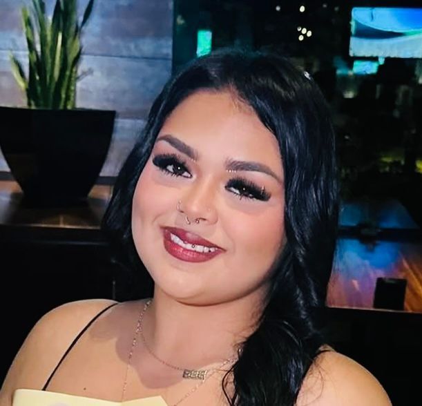 A woman with long black hair is smiling for the camera.