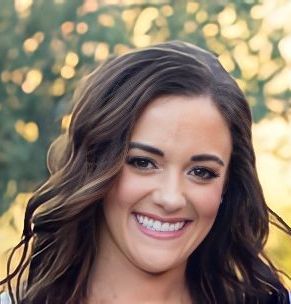 A woman with long brown hair is smiling for the camera.