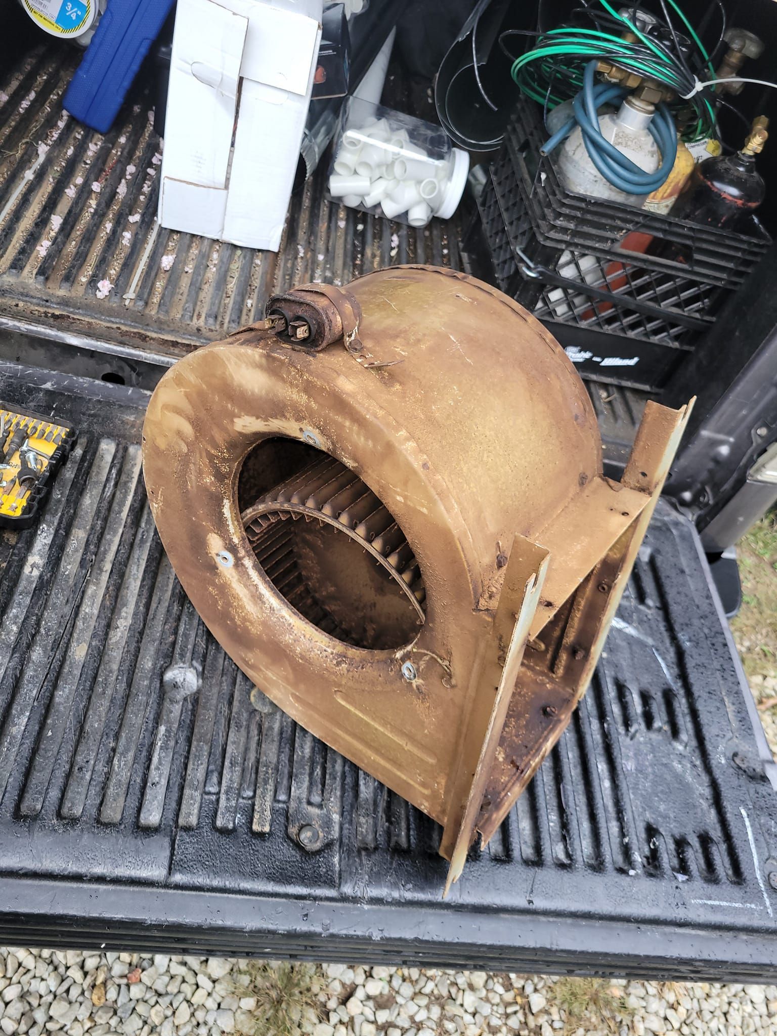 A rusty blower is sitting in the back of a truck.