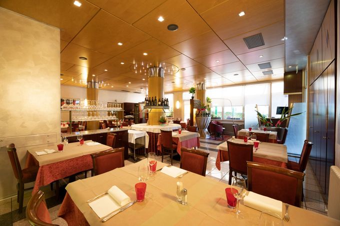 Una sala da pranzo con pareti in blocchi di cemento bianchi e travi in ​​legno a vista, arredata con un tavolo per otto persone e sedie marroni.