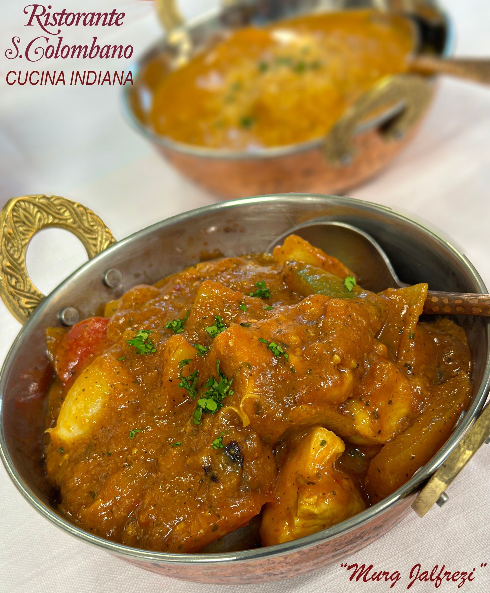 Due ciotole di rame piene di curry indiano, guarnite con erbe fresche, su uno sfondo bianco.
