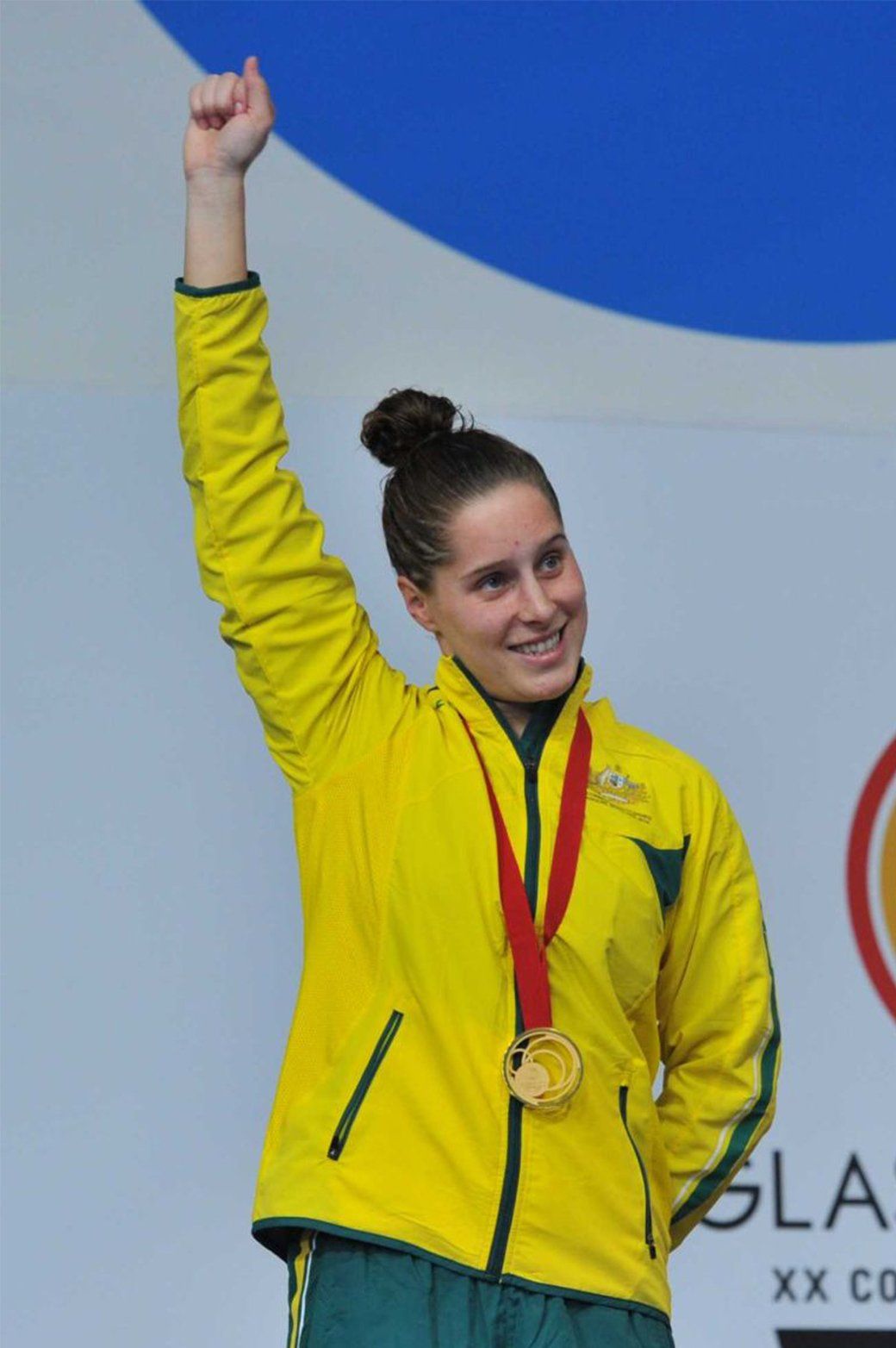 A woman in a yellow jacket with a gold medal around her neck