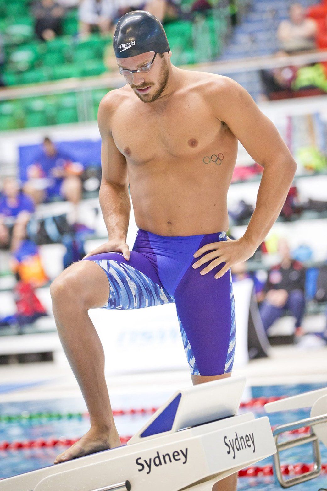A man is standing on a starting block in a swimming pool.