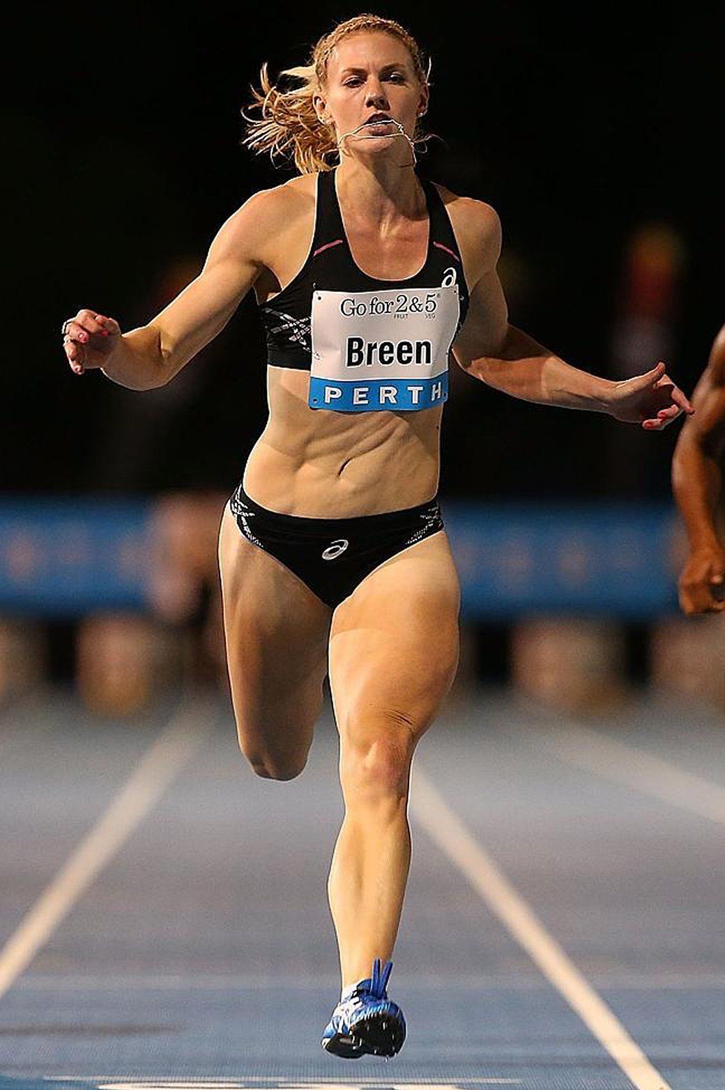 A woman running on a track with the name breen on her shirt