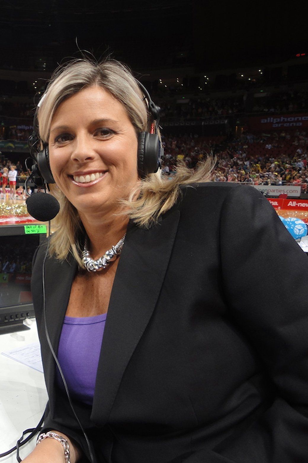 A woman wearing headphones and a microphone is smiling