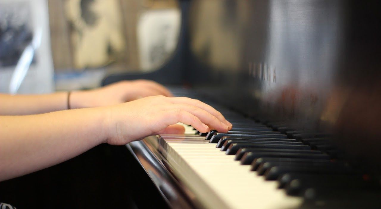 a person is playing a piano with their hands on the keys .