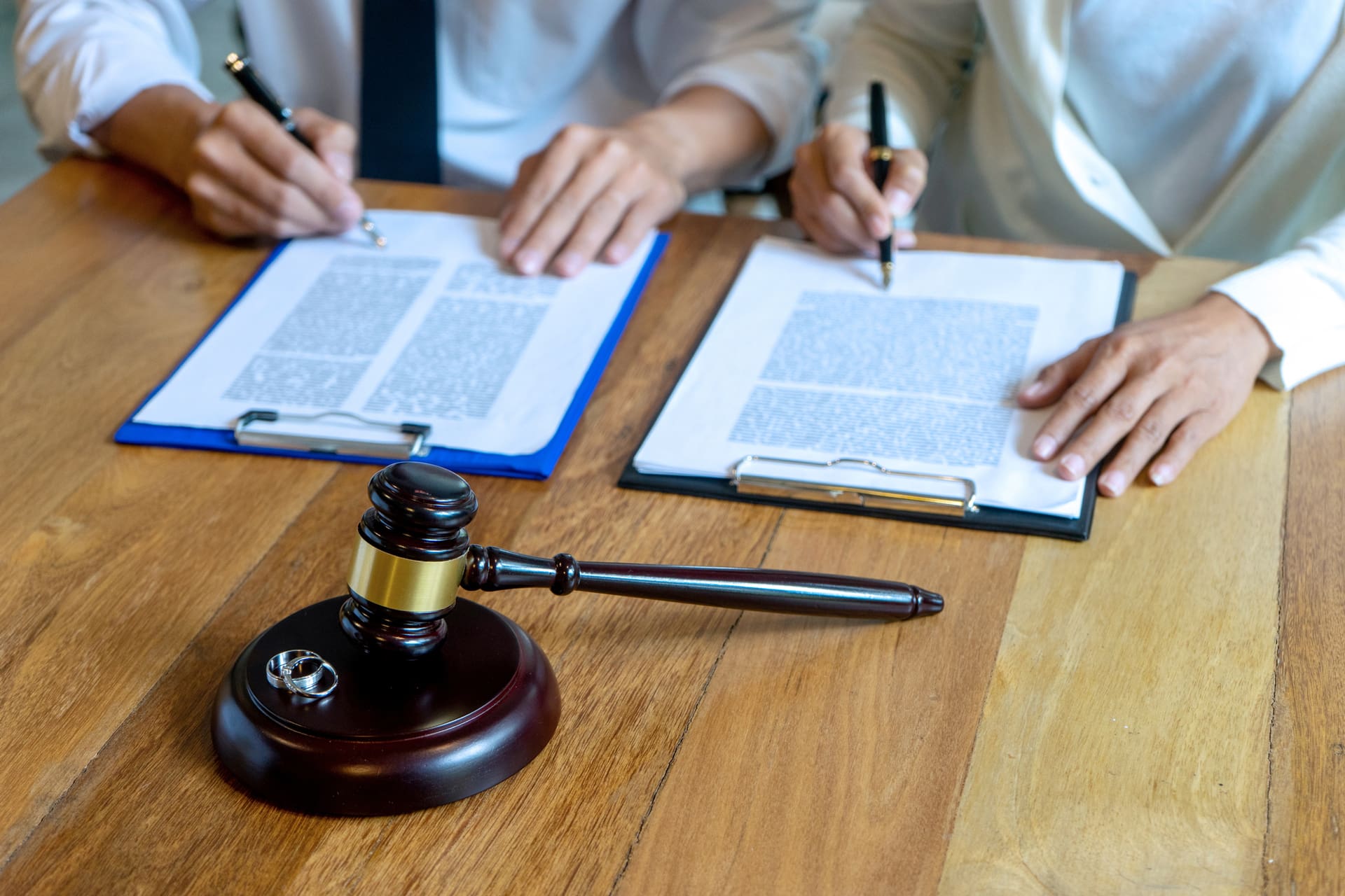 A couple of people are sitting at a table with papers and a judge 's gavel.