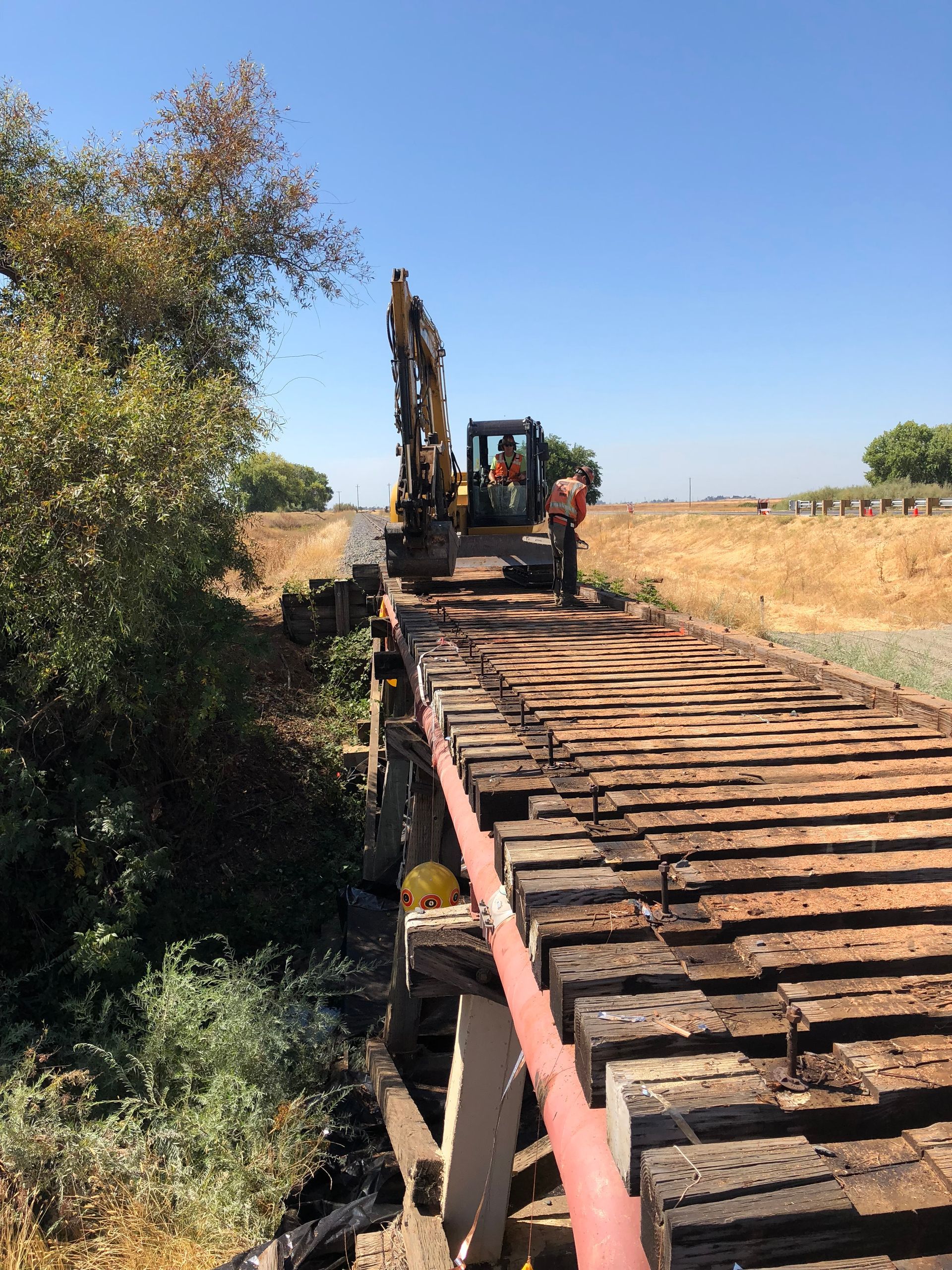 A Man Is Standing on a Wooden Bridge Next to an Excavator — Chicago, IL — Sterling Holloway Demolition