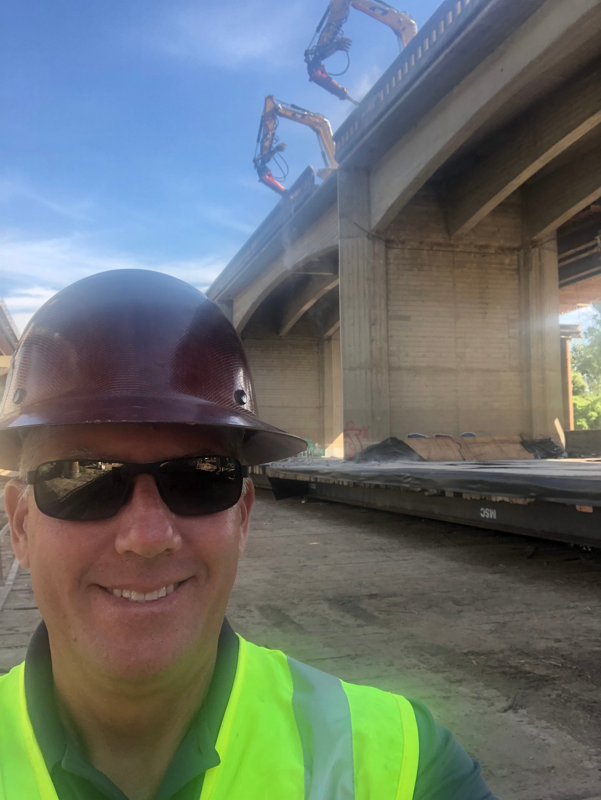 A Man Wearing a Hard Hat Standing in Front of a Bridge Under Construction — Chicago, IL — Sterling Holloway Demolition