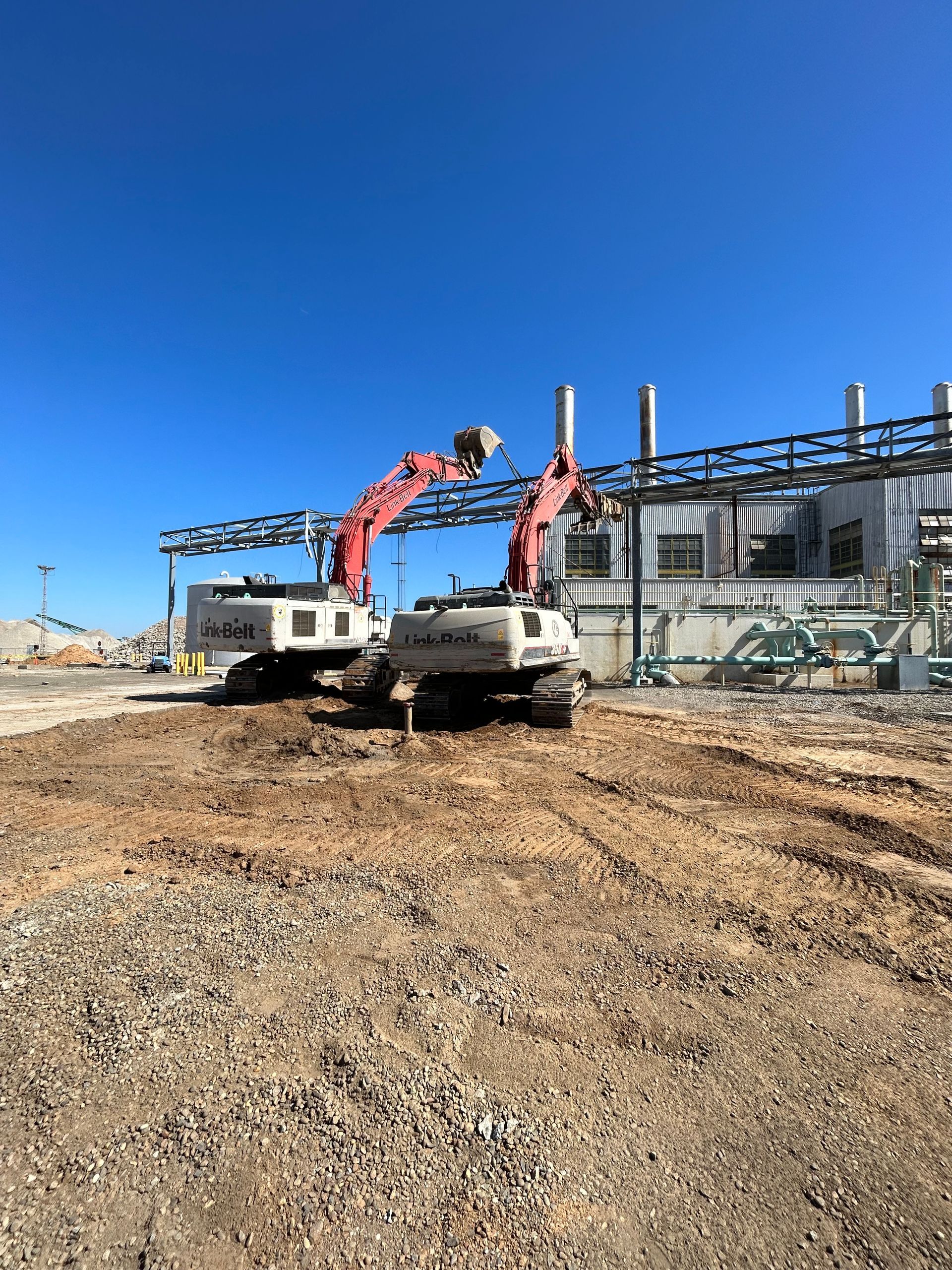 Two Construction Trucks Are Parked in a Dirt Field — Chicago, IL — Sterling Holloway Demolition