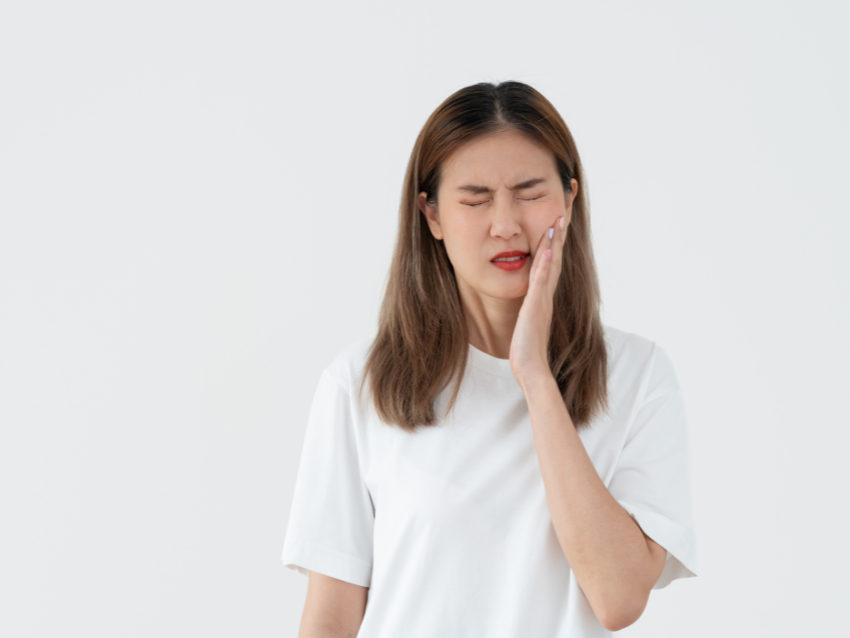 A woman is holding her face in pain because of a toothache.