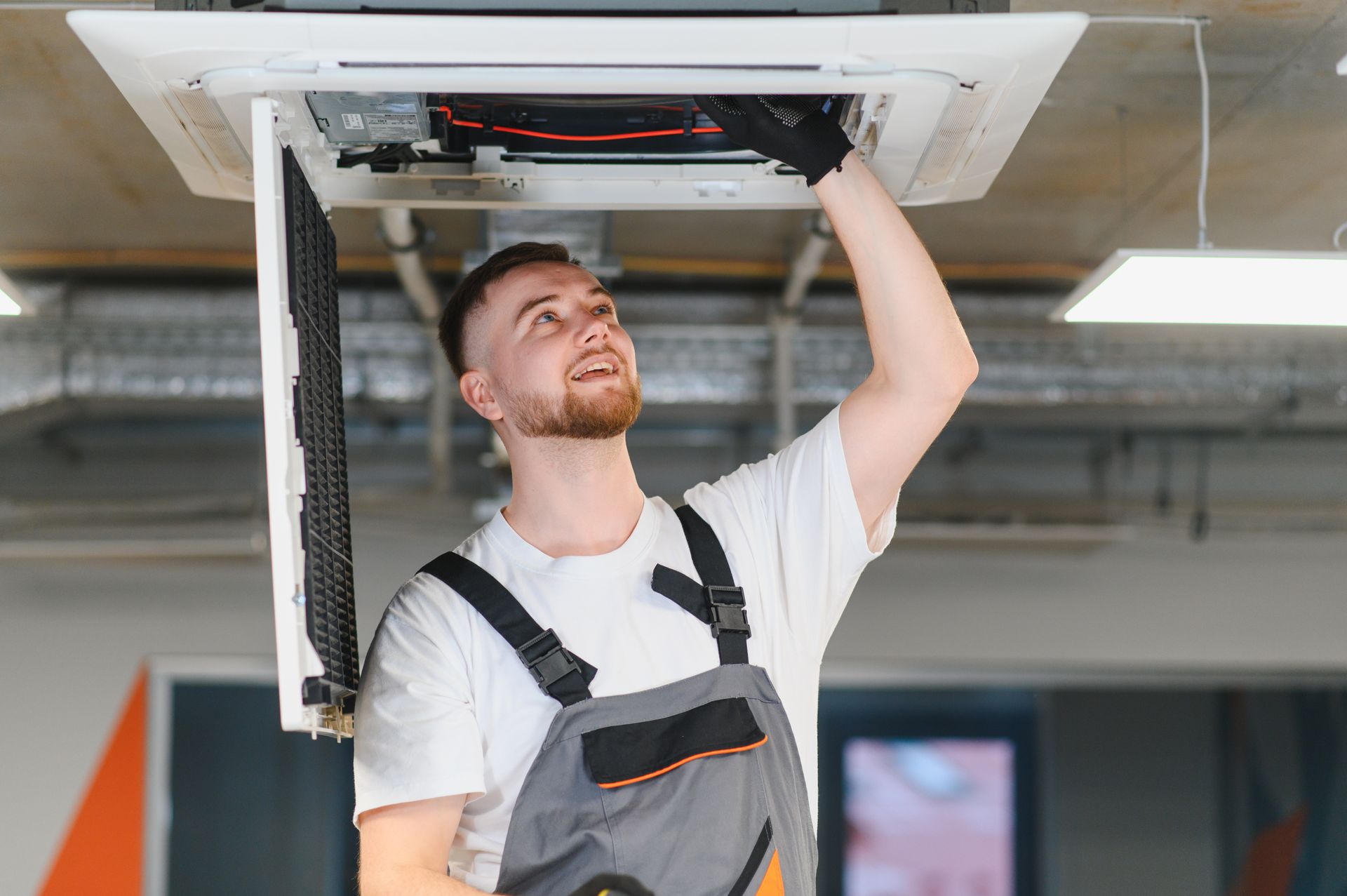 HVAC technician servicing ceiling air conditioning unit.