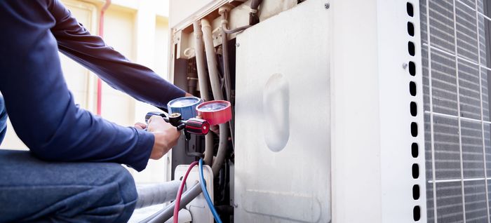 Technician checking an air conditioner, measuring equipment for filling air conditioners. Technician checking an air conditioner, measuring equipment for filling air conditioners.