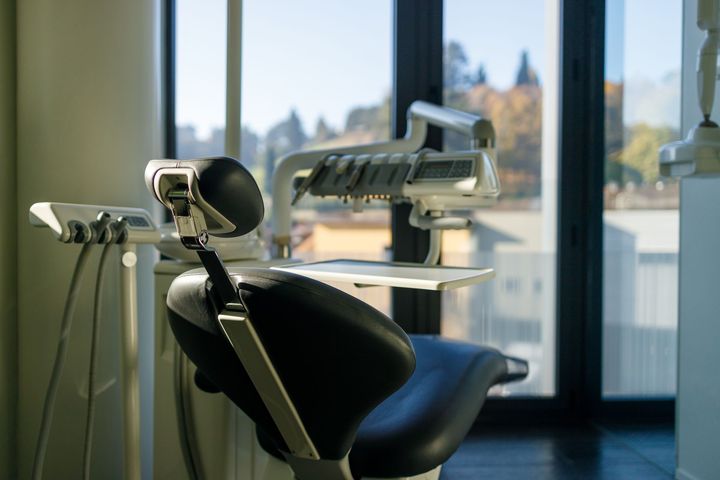 Una poltrona odontoiatrica è posizionata davanti a una finestra in uno studio dentistico.