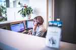 Una donna è seduta alla scrivania e parla al cellulare.
