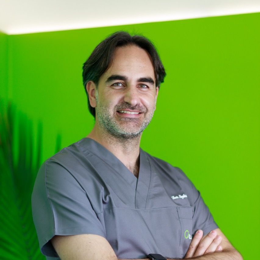 Dr. Alessio Franchina Un uomo in camice è in piedi con le braccia incrociate davanti a uno sfondo verde.