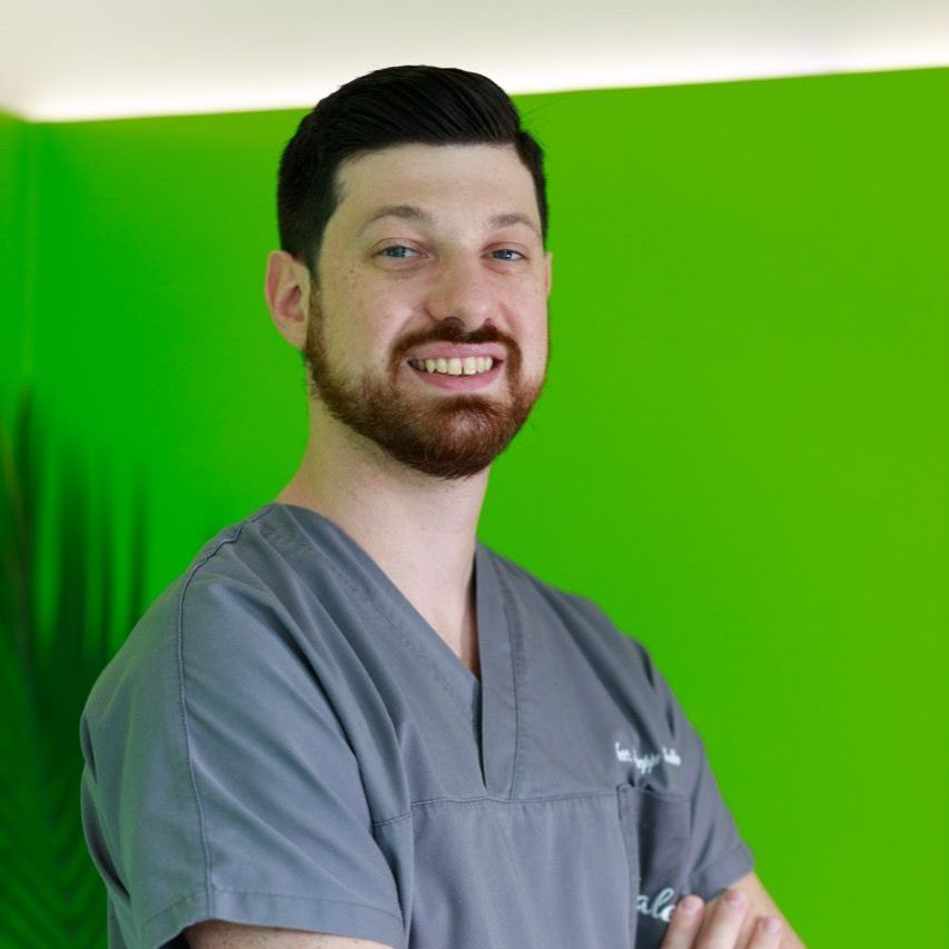 Dr. Alessio Franchina Un uomo in camice è in piedi con le braccia incrociate davanti a uno sfondo verde.