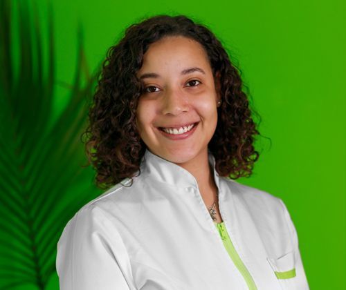 Una donna in camice bianco sorride davanti a uno sfondo verde.