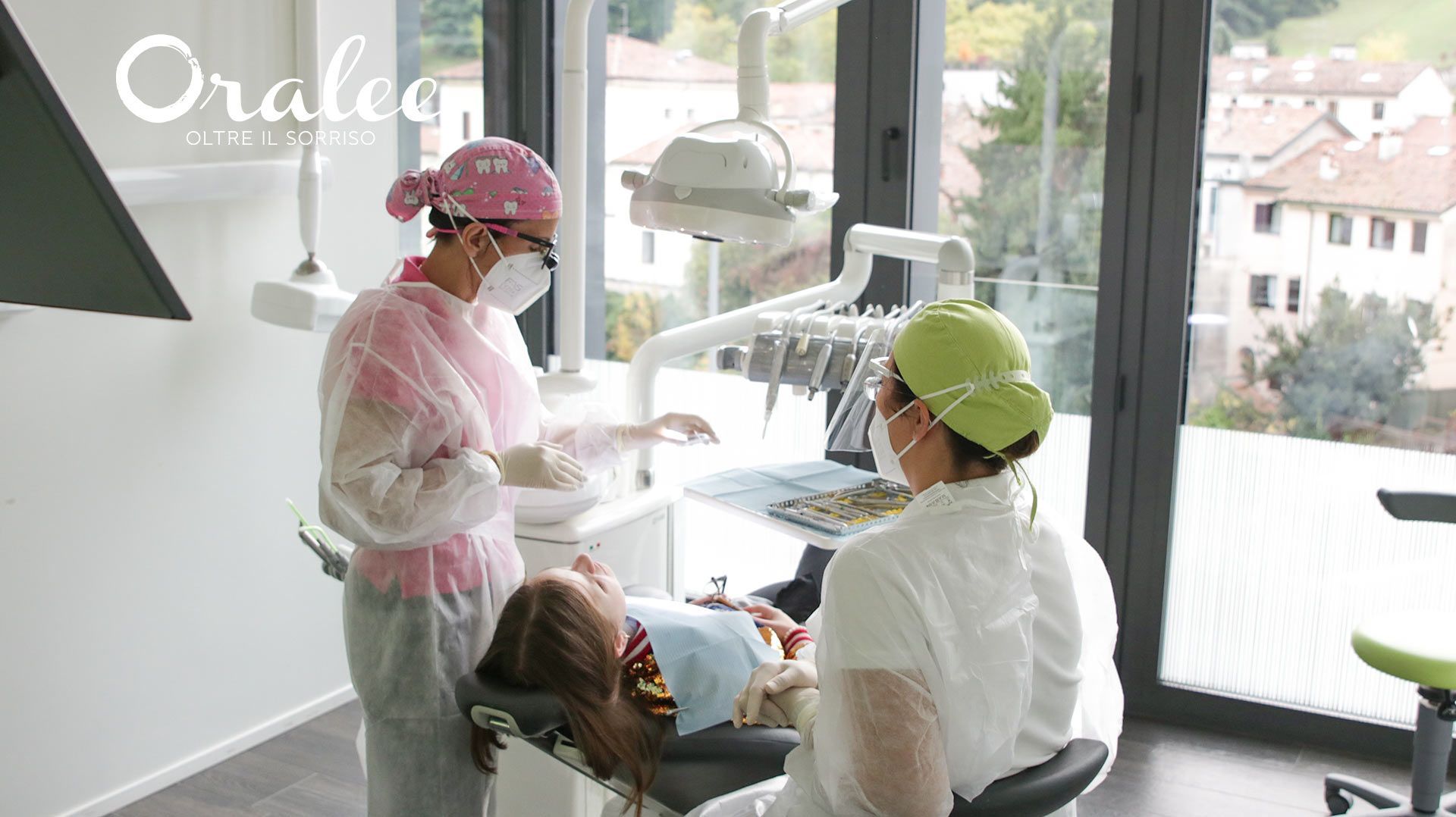 A woman is sitting in a dental chair getting her teeth examined by two dentists.
