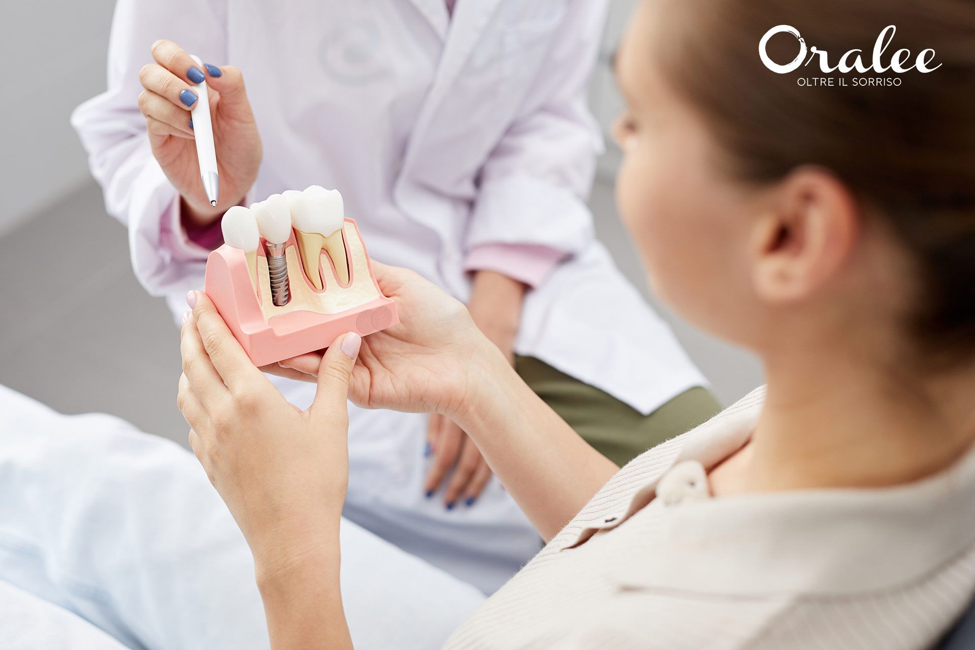 Una donna è seduta sulla poltrona del dentista e osserva un modello di denti.
