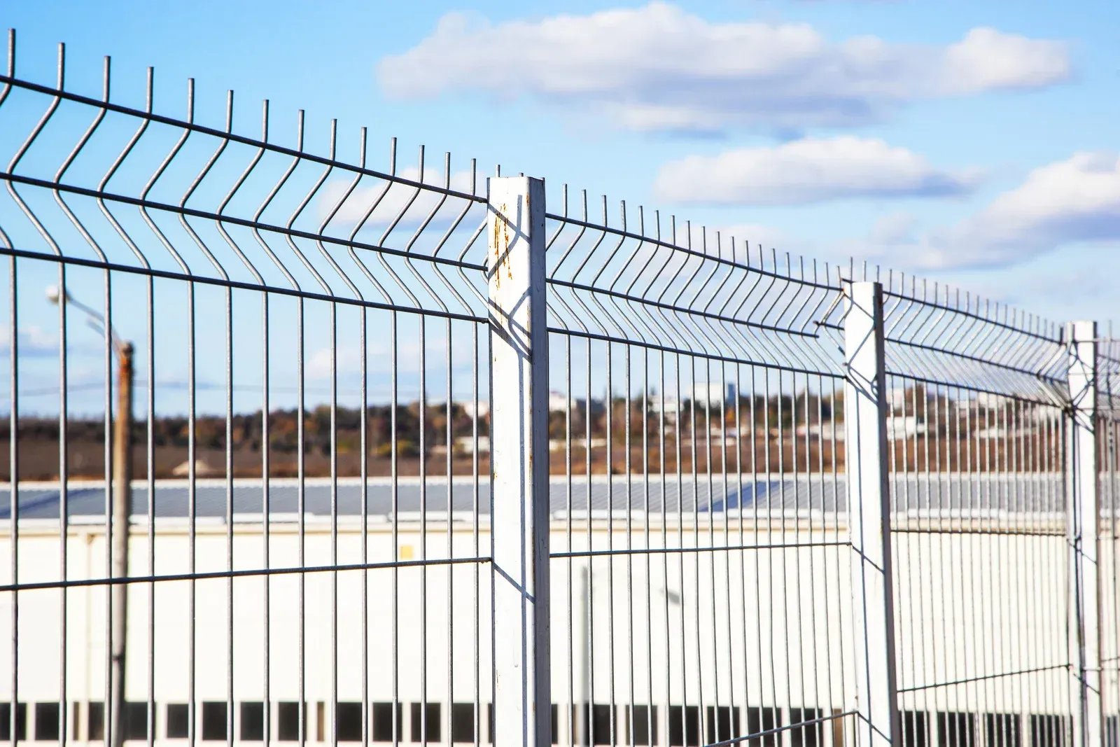 Barbed wire fence against a cloudy blue sky.