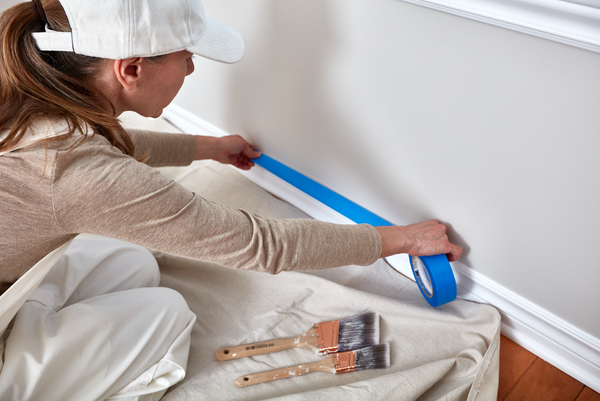 Interior painter preparing the walls and taping off the baseboard