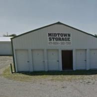 Midtown Storage facility with white metal siding and several closed garage-style storage unit doors.