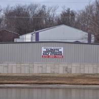 A gray metal storage facility with a sign reading 