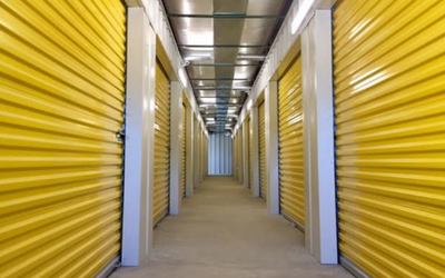A long, narrow indoor hallway lined on both sides with many closed, bright yellow metal storage unit doors.