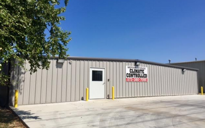A gray metal storage building with a central white door and a sign reading 