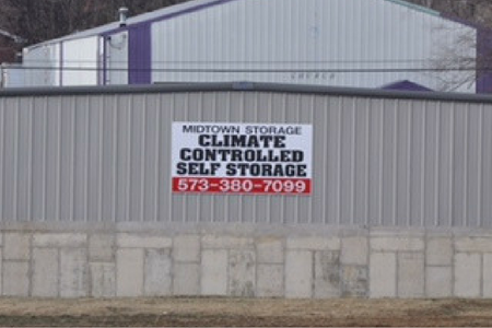 A sign for Midtown Storage on a corrugated metal fence reads, 