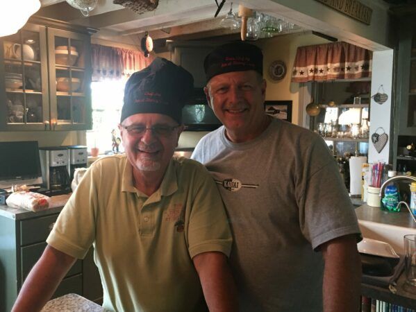 Two men wearing chef hats are posing for a picture in a kitchen